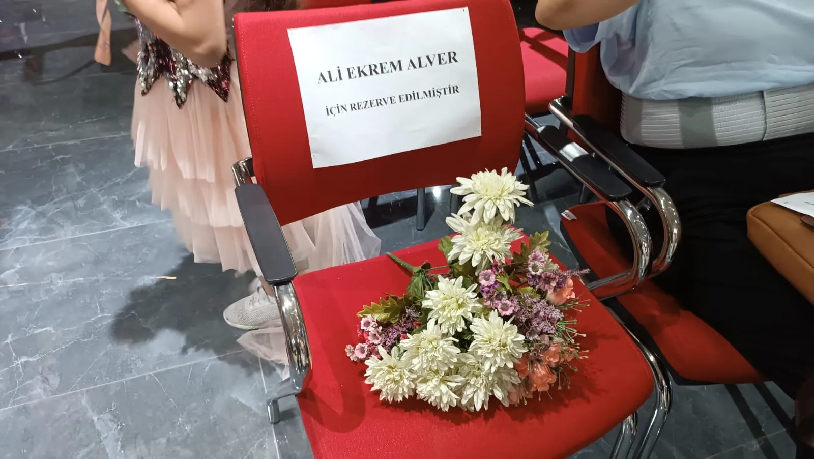 Ali Ekrem Alver için rezerve edilmiş, üzerine çiçekler bırakılmış kırmızı koltuk